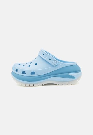 Clog azul claro com orifícios de ventilação, tira ajustável, sola elevada e materiais de borracha texturizados. Sola branca com padrão gulado.