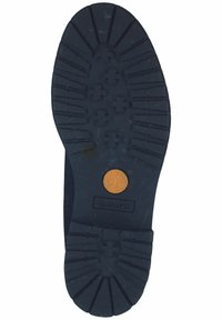 Suela de goma negra con patrones de relieve profundos para tracción, con un logo circular de Timberland en naranja en el centro.