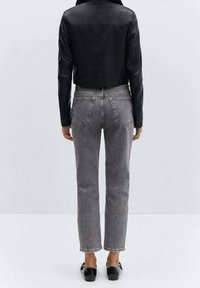 Chaqueta corta de cuero negro sobre jeans de tiro alto grises. Los jeans cuentan con bolsillos traseros y un corte recto. Zapatos negros completan el look.