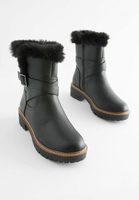 Bottines noires en cuir texturé avec un revers en fausse fourrure, détail de boucle et semelle en caoutchouc dotée d'un talon robuste.