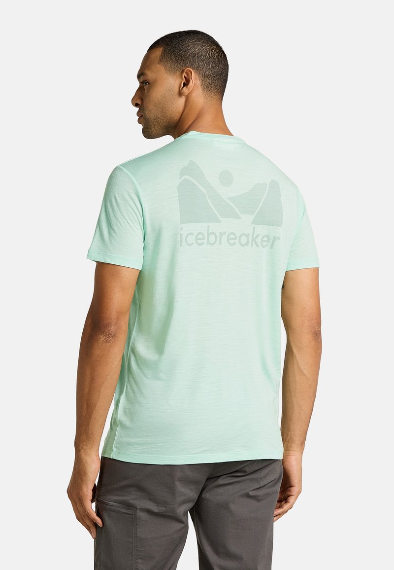 Camiseta de manga corta verde menta claro con un gráfico de montaña y el logo "icebreaker" en la parte posterior. Textura suave, corte casual.