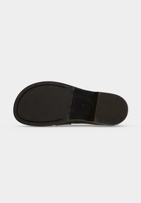 Semelle d'une chaussure habillée en cuir marron avec une semelle en caoutchouc noir lisse et un petit talon, présentée sur un fond clair.