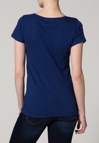 Marinblå t-shirt med kort ärm och rund halsringning, mjuk textur och subtila sömdetaljer på baksidan. Bärs med mörka jeans.