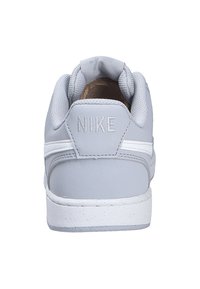 Scarpe Nike con tomaia in pelle grigia, colletto imbottito e suola in gomma bianca. Presenta un tallone testurizzato e un marchio grigio.