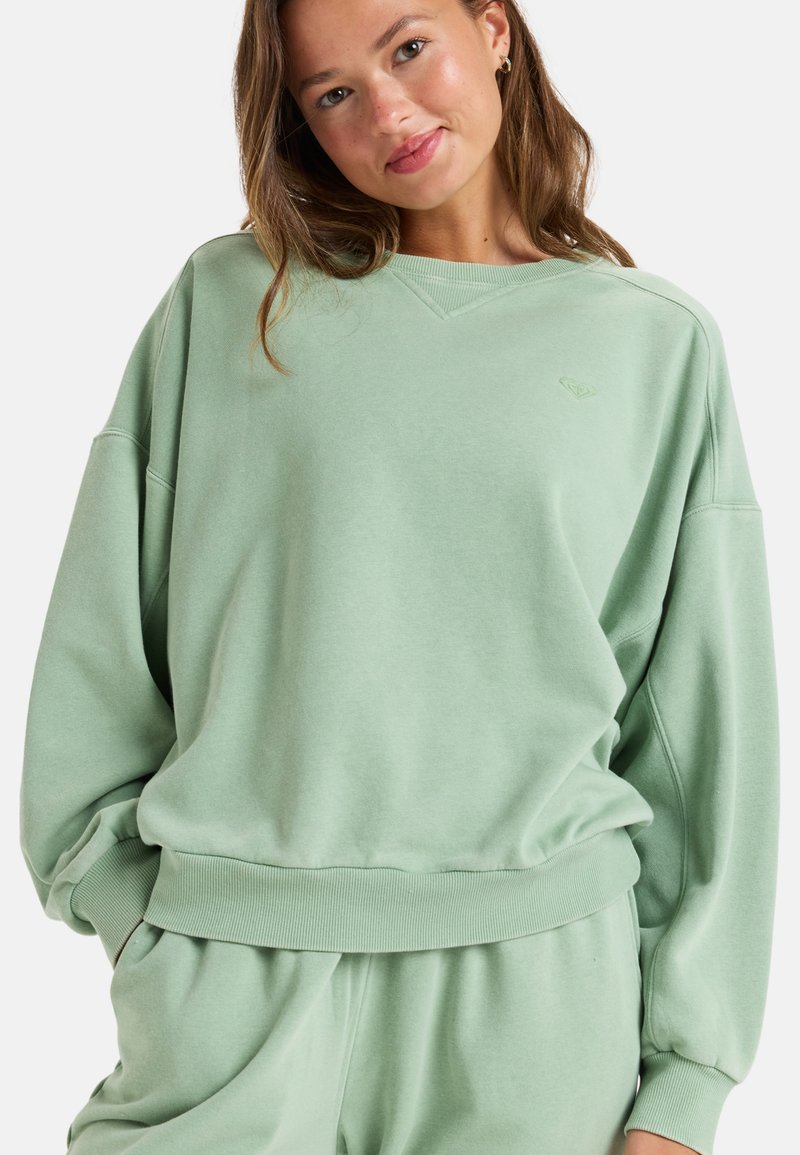 Light green sweatshirt with a relaxed fit, ribbed cuffs, and hem. Features a v-neckline and subtle logo detail on the chest. Soft texture.