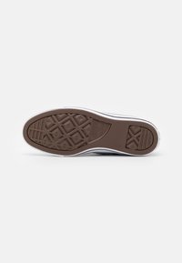 Brown rubber sneaker sole with diamond and horizontal tread patterns. White sidewall and branding detail. Smooth texture.