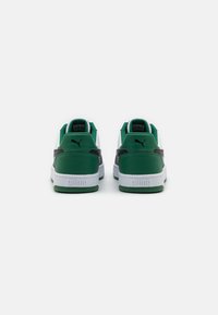Puma sneakers med hvid overdel, grøn hæl og accenter, grå sidepanel og tyk hvid sål; branding på hælen.