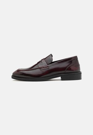 Bordeaux lakleren loafers met een verhoogde naad en een platte zwarte rubberen zool, ontworpen met een instapstijl en minimale accenten.