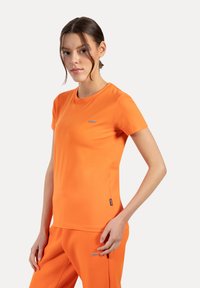 Oranje katoenen t-shirt met korte mouwen, ronde hals en kleine logodetail op de borst. Glad textuur en aansluitend ontwerp.