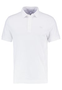 Polo shirt en coton blanc à manches courtes, avec un col et un logo brodé subtil sur la poitrine. Texture lisse et coupe classique.