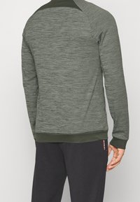Sudadera texturizada de color verde oscuro con cuello redondo acanalado y puños. Presenta un color sólido con sutiles variaciones en la tela.