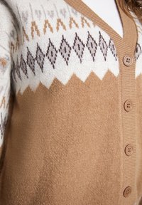 Cardigan in maglia marrone con un motivo geometrico bianco e beige, scollo a V e sei bottoni tondi sul davanti per la chiusura.
