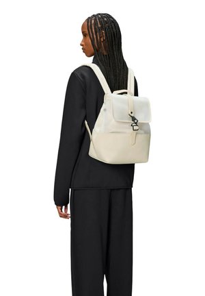 Zaino beige chiaro con pattina, chiusura a fibbia e spalline regolabili. Realizzato in materiale liscio, presenta un design minimalista e un marchio discreto.