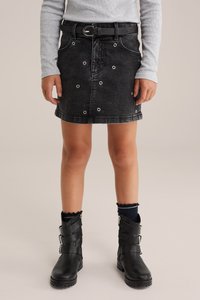 Črna jeans mini krila z srebrnimi okrasnimi grometami, ravne rezane, z usnjeno pasom. Ujemajoče se z črnimi gležnjarji in mornarsko modrimi nogavicami.