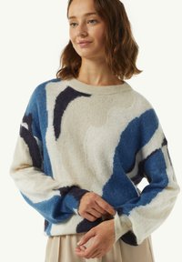 Strickpullover mit lockerer Passform, der eine Mischung aus Blau-, Marine- und Cremetönen in abstrakten Mustern präsentiert. Weicher, strukturierter Stoff.