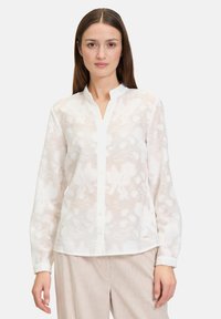 White, lightweight blouse with a floral pattern, button front, and mandarin collar. Long sleeves with buttoned cuffs. Smooth, sheer texture.