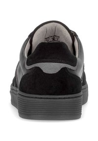 Zwarte sneaker met een glad leren bovenwerk, suède accenten en een gestructureerde rubberen zool. De achterkant toont een gevoerde kraag en logo-detail.
