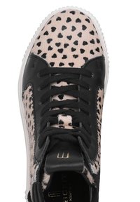 Schwarze Sneaker mit einem strukturierten pinken Obermaterial, das mit schwarzen herzförmigen Flecken versehen ist, schwarzen Schnürsenkeln, einer weißen Gummisohle und einem dezenten Branding-Detail.