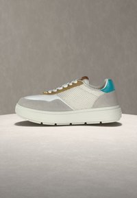 Χαμηλά αθλητικά παπούτσια με λευκό δίχτυ, γκρι σουέτ λεπτομέρειες, ταμπά στοιχεία, τιρκουάζ ταμπελάκι στη φτέρνα, λευκά κορδόνια και χοντρή λευκή σόλα πάνω σε φωτεινή επιφάνεια.