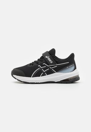 Scarpa da atletica nera con accenti bianchi, tomaia in mesh traspirante, colletto imbottito, strap regolabile in velcro e un rinforzo sul tallone grigio per supporto.