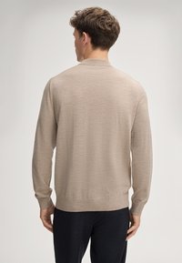 Beige gestrickter Pullover mit langen Ärmeln, gerippten Bündchen und Saum. Verfügt über einen runden Halsausschnitt und eine glatte, weiche Textur.