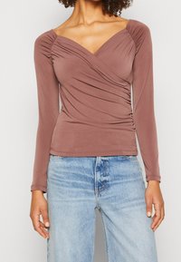 Langarmoberteil in Mauve, mit einem Wickeldesign und gerafften Akzenten an den Schultern und der Seitennaht, aus einem weichen, dehnbaren Stoff gefertigt.