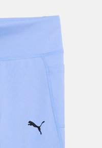 Ανοιχτό μπλε αθλητικό κολάν με ψηλή μέση, πλαϊνή τσέπη και μαύρο λογότυπο Puma κοντά στο τελείωμα.