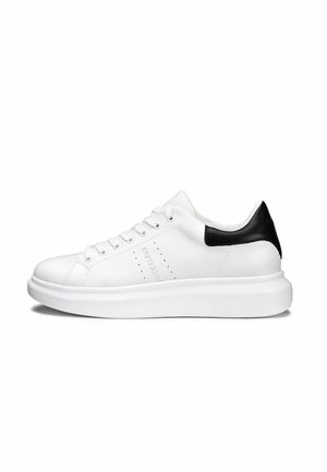 Sneaker in pelle bianca con accentuazione nera sul tallone. Caratterizzato da dettagli perforati sul lato e una suola spessa bianca. Design classico con lacci.