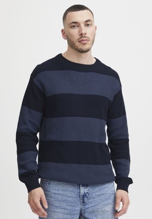 Pull en jersey bleu marine avec des rayures horizontales dans des teintes sombres et claires, col rond et manches longues.