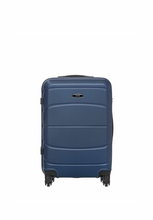 Twarda walizka w ciemnoniebieskim kolorze, wyposażona w cztery obrotowe kółka i górny uchwyt, stojąca pionowo na białym tle.