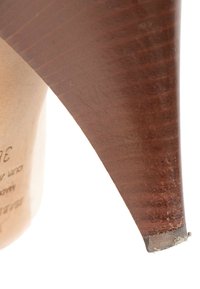 Gros plan de l’extrémité usée du talon d’une chaussure à talon haut en cuir marron montrant la texture et de légères marques d’abrasion.