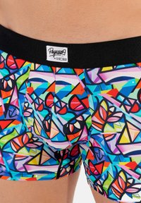 Colorful swim shorts with an abstract geometric pattern in blue, red, green, and black. Features a black elastic waistband and a logo tag.