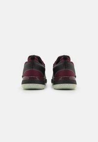 Zwarte en bordeaux sportieve schoenen met een geperforeerde mesh bovenwerk, een gewatteerde zool en een rubberen buitenzool met een profiel voor grip.