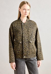 Leopardmønstret jakke i brun og sort, med trykknaplukking, to forlomme og en avslappet passform. Teksturlaget stoff.
