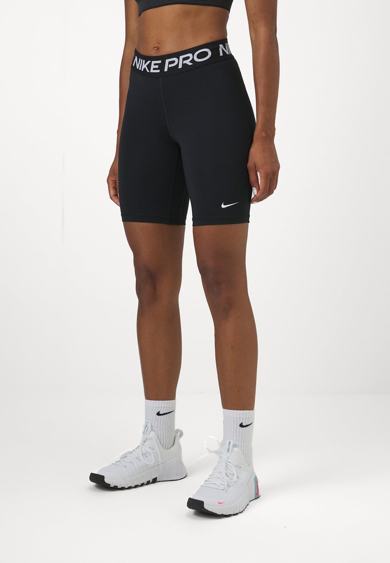 Crne Nike Pro biciklističke kratke hlače s bijelim logotipom na pojasu i sa strane, glatka tkanina, tijesno krojenje i dužina do sredine bedara.