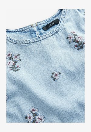 Hellblaue Jeansbluse mit Blumenstickerei in Weiß und Rot, runder Halsauschnitt und subtiler Textur. Markenlabel innen sichtbar.