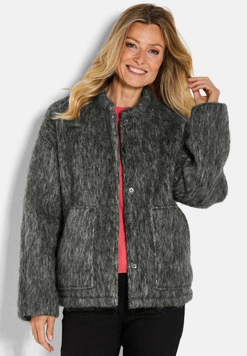 Grijze, fluffy textuur jack met grote knopen, opgerolde mouwen, twee voorkruiszakken en een ronde kraag, gelaagd over een roze top.