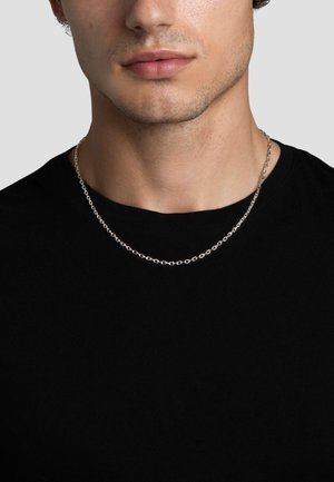 Silberne Kettenhalskette mit runden Gliedern, kombiniert mit einem schwarzen T-Shirt. Nahansicht zeigt die glatte Textur und die gleichmäßige Anordnung im Design.