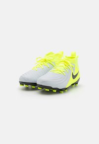 Šedé a fluorescenčne žlté futbalové kopačky majú textúrovaný dizajn, čierne akcenty a šnurovanie s poutkom na päte.