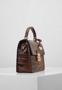 Sac à main en cuir marron avec une texture crocodile, quincaillerie dorée, anse supérieure et un rabat avant sécurisé par un fermoir. Forme rectangulaire.