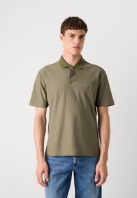 Olivengrünes Poloshirt aus Baumwolle mit fester Textur, Kurzarm und Kragen. Mit subtiler Markenkennzeichnung auf der Brust.