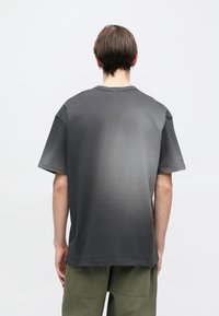 Γκρι μπλουζάκι ombre με κοντά μανίκια και στρογγυλή λαιμόκοψη. Το ύφασμα φαίνεται απαλό· το χρώμα μεταβαίνει από σκούρο σε ανοιχτό γκρι.