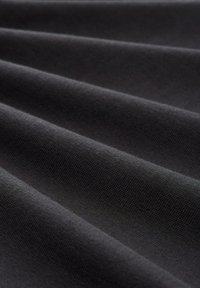 Tela negra con una textura suave, que presenta un diseño plegado que crea líneas paralelas suaves y una profunda intensidad de color.