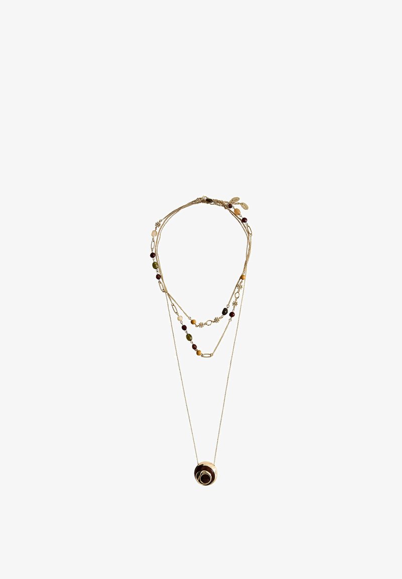 Collier en or délicatement superposé avec de petites perles colorées et des breloques, avec un pendentif rond avec un motif en spirale sur la chaîne la plus longue.