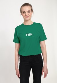 Zielony bawełniany t-shirt z krótkimi rękawami i okrągłym dekoltem, z białym napisem "IRISH." umieszczonym na środku przodu.