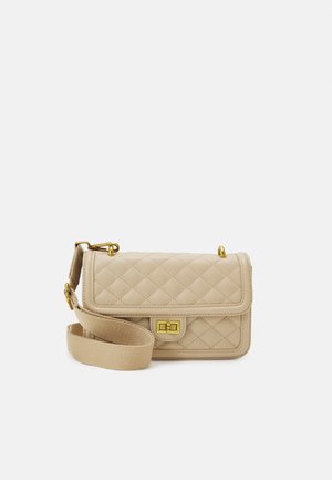 Sac à épaule matelassé beige avec fermoir doré et sangle en tissu réglable sur un fond clair uni.