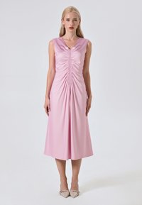 Ärmelloses pinkes Kleid mit Raffung vorne, V-Ausschnitt und knielangem Saum. Glattes Material und ein subtiler Schlitz heben das Design hervor.