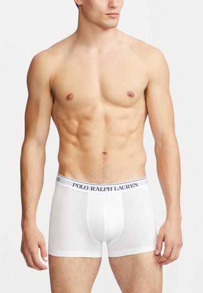 Boxeri din bumbac alb cu un design ajustat, având un bandă logo contrastantă de culoare bleumarin la talie și o textură netedă, elastică.