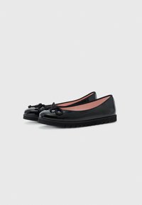 Ballerines en cuir verni noir avec un bout rond, détail de nœud décoratif à l'avant et semelle en caoutchouc. L'intérieur est rose.