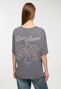 Szara, oversize t-shirt z grafiką na plecach przedstawiającą klucze, misia oraz tekst "Ciao Amore!" w jasnoróżowym kolorze. Wykonana z miękkiej bawełny, luźny krój.